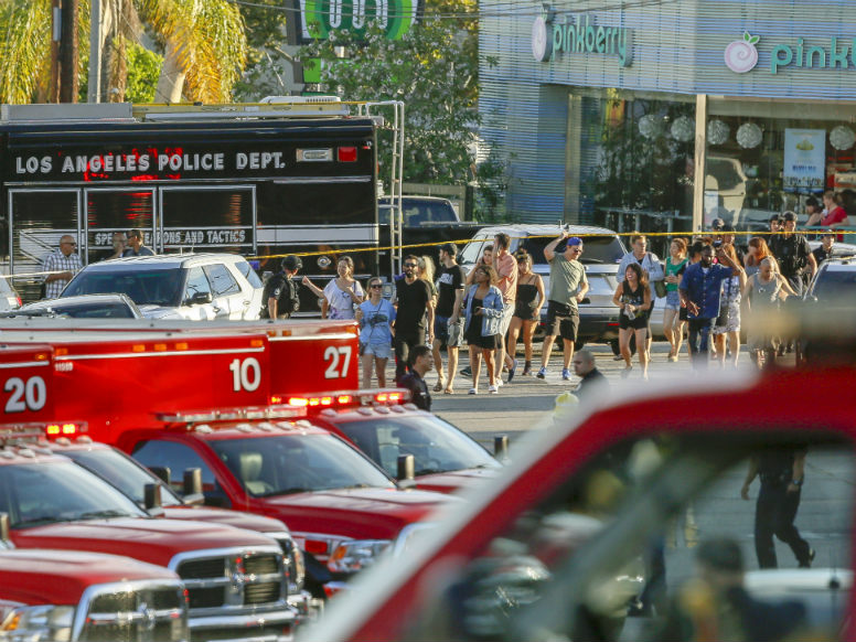 Los Angeles Police SWAT officers escort a group of people who were held for their safety by police across businesses surrounding a Trader Joe's supermarket, after a gunman held dozens of people hostage inside the store.